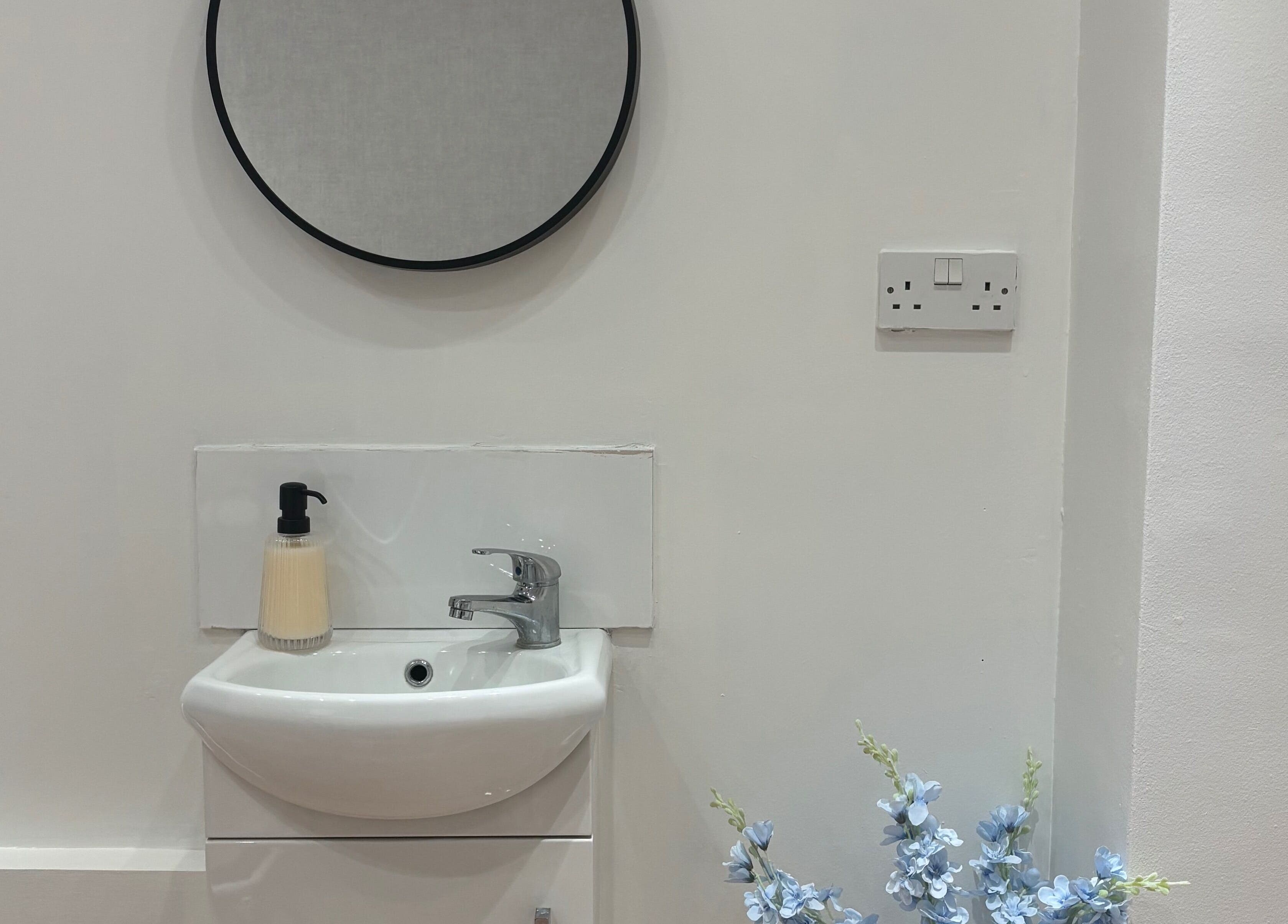 Modern vanity area at By Ells, Redditch, England, GB. Features round mirror and elegant sink.