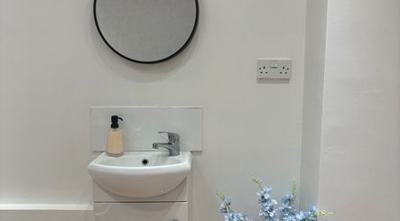 Modern vanity area at By Ells, Redditch, England, GB. Features round mirror and elegant sink.