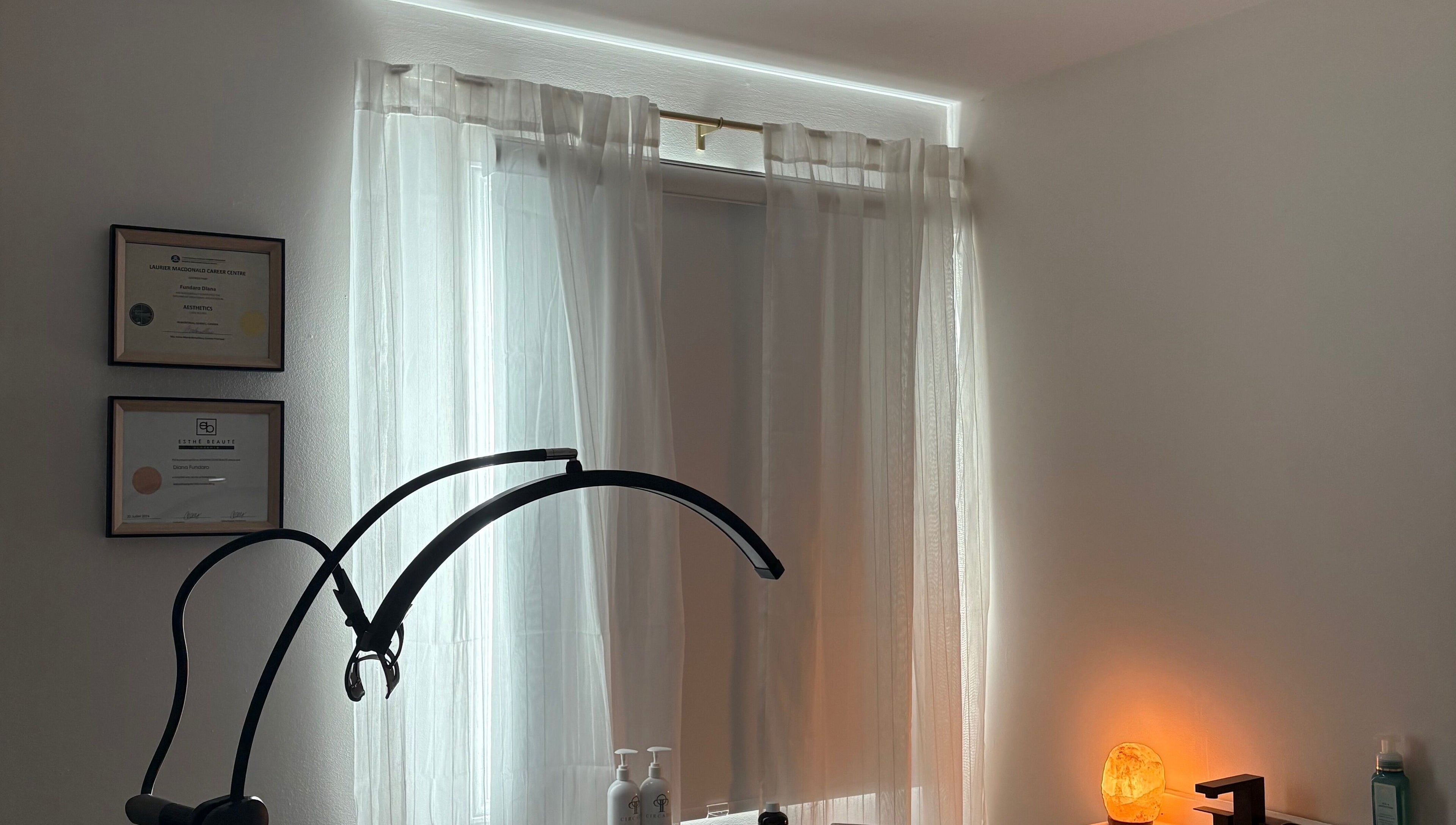 Calm treatment room at VitaGlow Esthétiques, Laval, Québec, CA with warm lighting and certificates displayed.