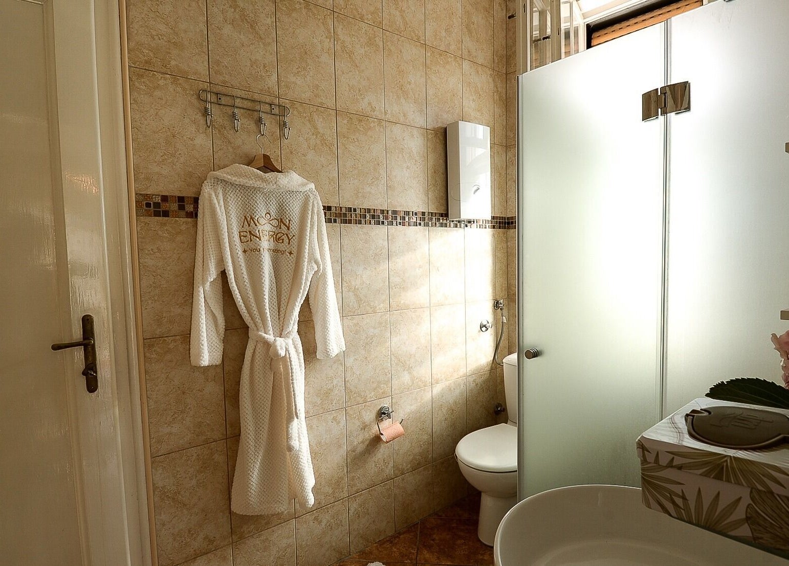 Elegant bathroom at Moon Energy, Beograd, RS, featuring a cozy white robe and modern amenities.