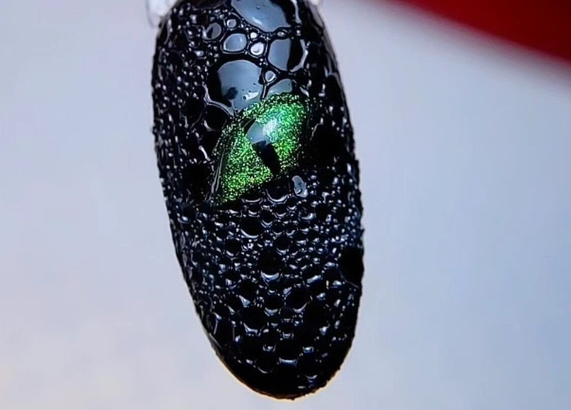 Nail art noir avec motif d'œil de reptile chez Patou Nails, Saint-Barthélemy, Auvergne-Rhône-Alpes, FR.