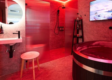 Luxurious spa room at Vita Health Club in North Willoughby, New South Wales, AU with red lighting and wooden tub.