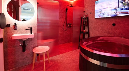 Luxurious spa room at Vita Health Club in North Willoughby, New South Wales, AU with red lighting and wooden tub.