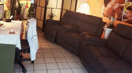 Comfortabele loungehoek bij Massagesalon Nostalgia, Alken, BE, met luxe stoelen en sfeervolle verlichting.