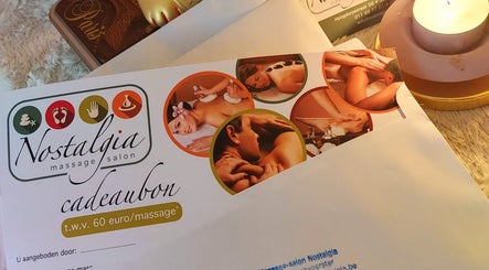 Cadeaubon van Massagesalon Nostalgia in Alken, BE, naast brandende kaars en decoratief ontwerp.