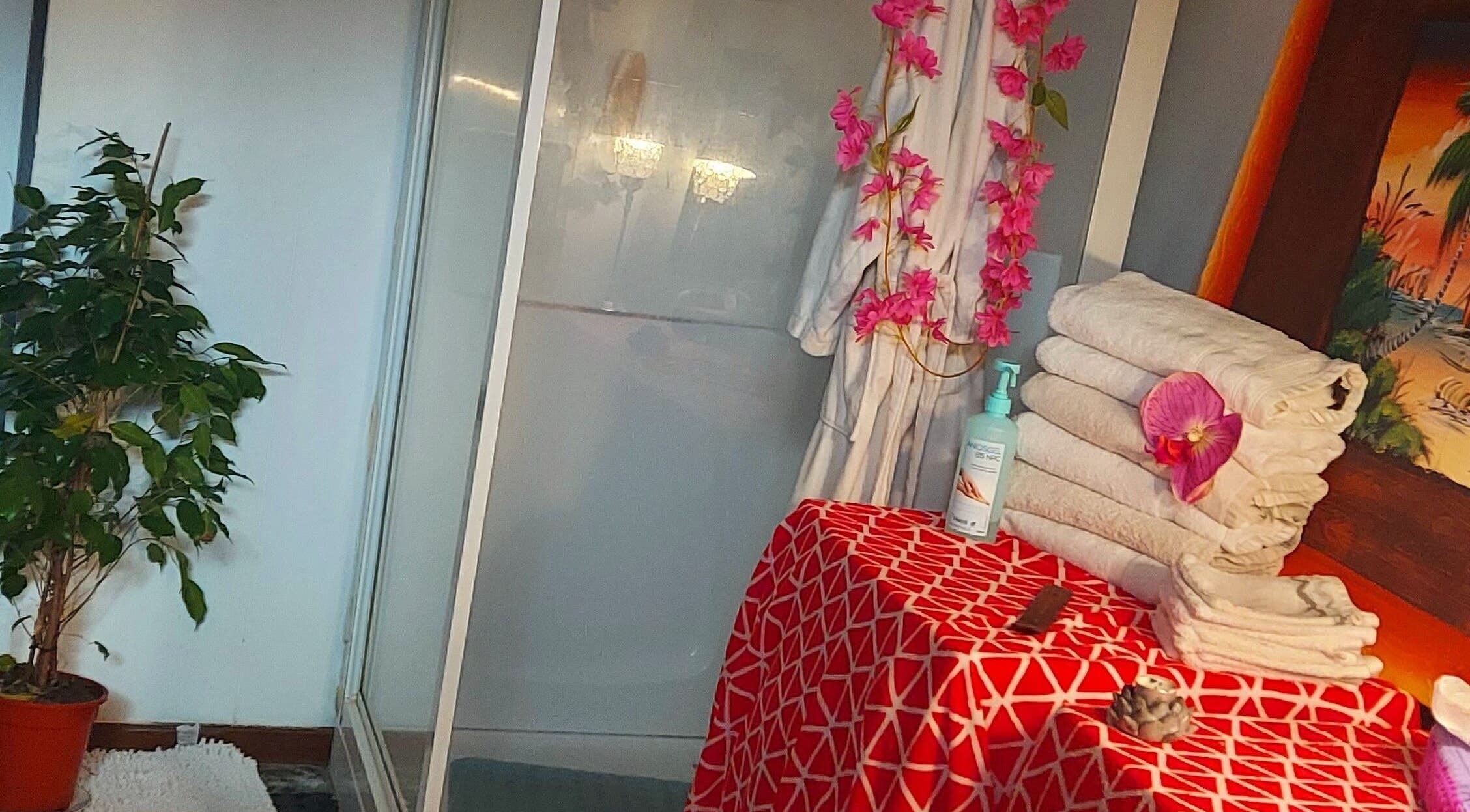 Wellnesshoek bij Massagesalon Nostalgia in Alken, BE. Handdoeken en plant voor ontspanning.