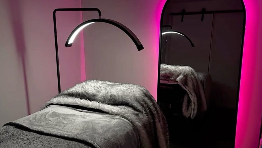 Luxurious treatment room at LASHOGRAPHER, Leicester, England, with pink LED lights and plush grey bedding.