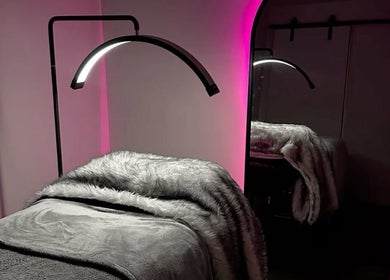 Luxurious treatment room at LASHOGRAPHER, Leicester, England, with pink LED lights and plush grey bedding.