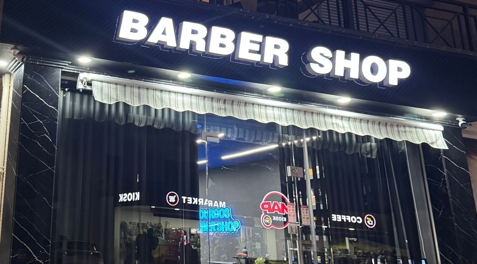 Το Νίκος Barber Shop στην Πάφο, Πάφος, CY φωτισμένο εξωτερικά τη νύχτα.