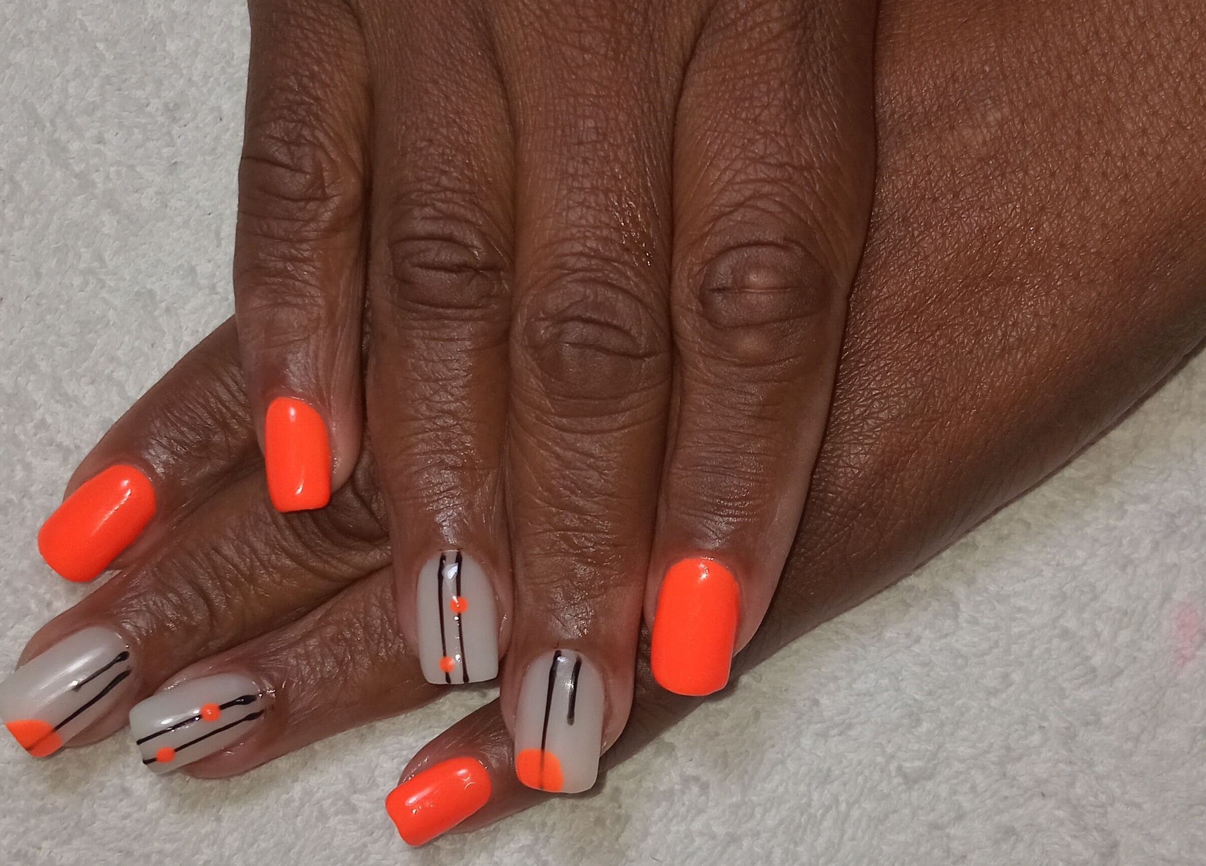 Bright orange and design nail art at Imbewuenhle Beautology, Benoni, Gauteng, ZA, showcasing expert manicures.