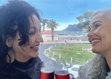 Smiling women with drinks at Innermost Wellbeing, Cape Town, Western Cape, ZA overlooking scenic views.