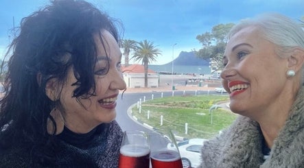 Smiling women with drinks at Innermost Wellbeing, Cape Town, Western Cape, ZA overlooking scenic views.