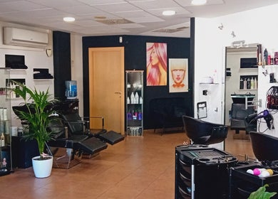 Interior moderno de Perruqueria Sant Jordi en Vilanova I La Geltrú, Cataluña, ES con sillas elegantes y decoración artística.
