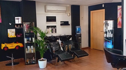 Interior moderno de Perruqueria Sant Jordi, Vilanova I La Geltrú, Cataluña, ES con sillas y productos de belleza.