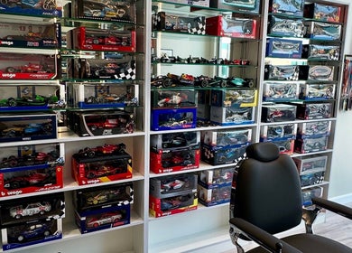Stylish Aura salon & spa in Al Janabiyah with model cars on display and sleek black chair.