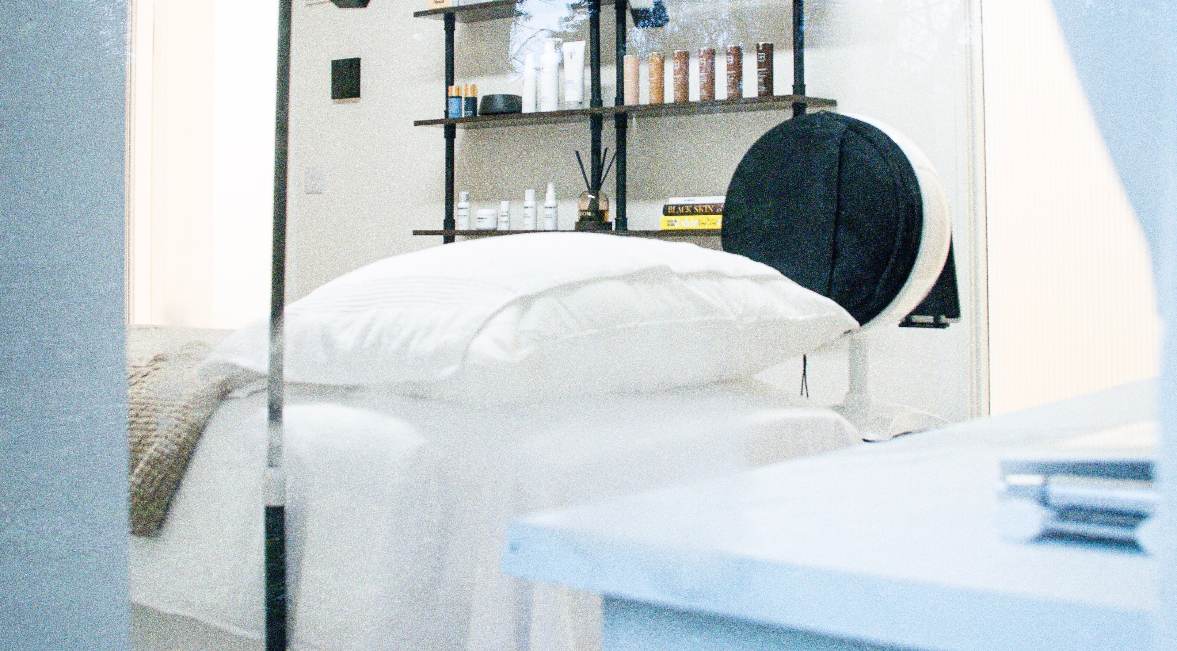 A cozy treatment room at Skin Orchid in London, England, GB, featuring a neatly made bed and skincare products.