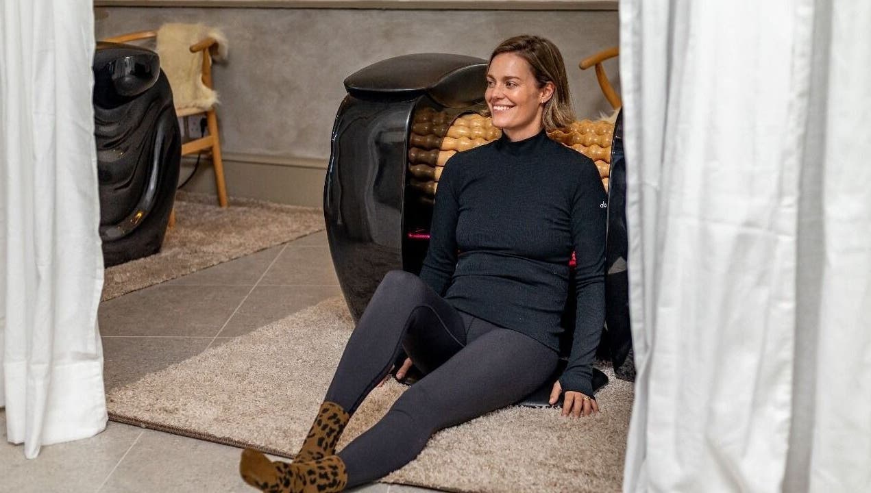 Woman relaxing at Roll and Ritual venue in Plettenberg Bay, Western Cape, ZA, sitting by a wellness machine.