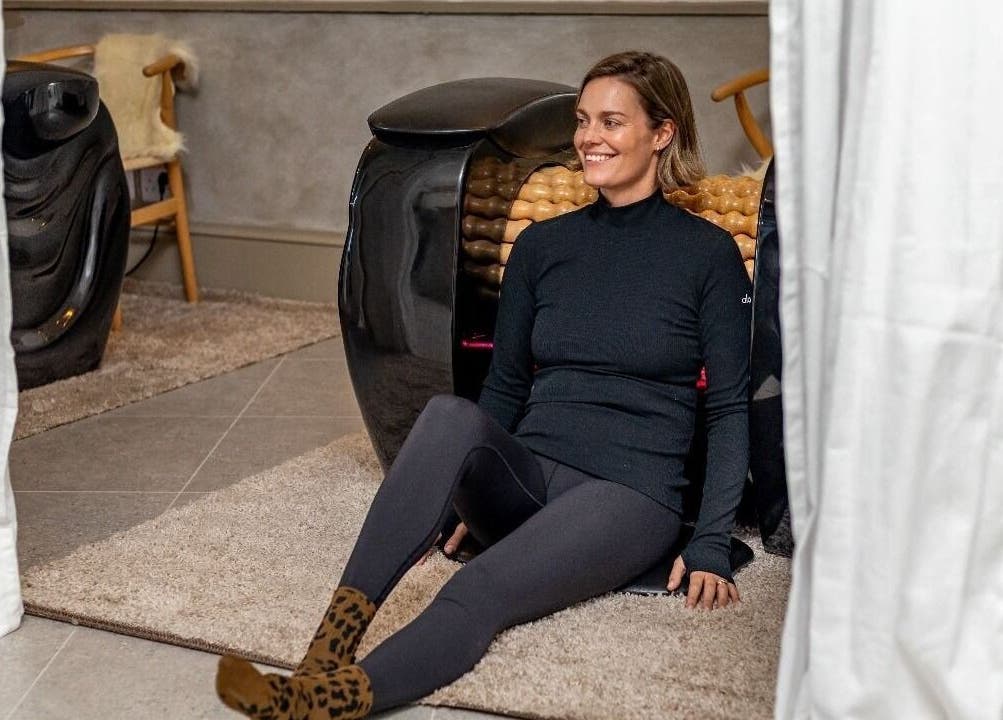 Woman relaxing at Roll and Ritual venue in Plettenberg Bay, Western Cape, ZA, sitting by a wellness machine.
