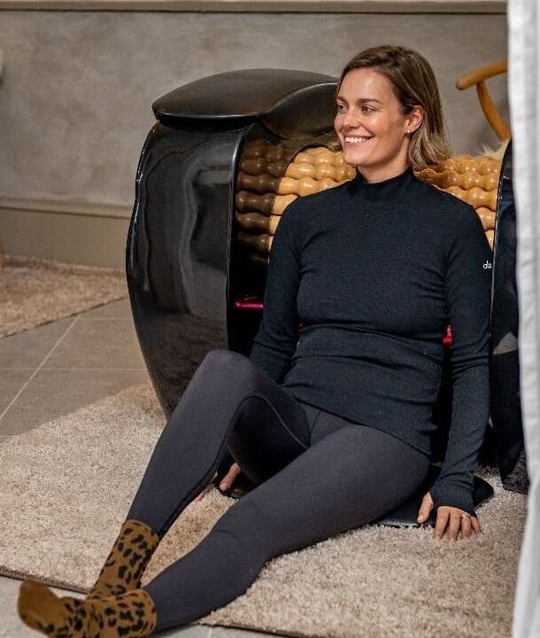 Woman relaxing at Roll and Ritual venue in Plettenberg Bay, Western Cape, ZA, sitting by a wellness machine.