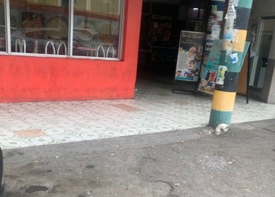 Entrance of Icons Barbershop in Kingston, St. Andrew Parish, JM with bold red exterior and tiled walkway.