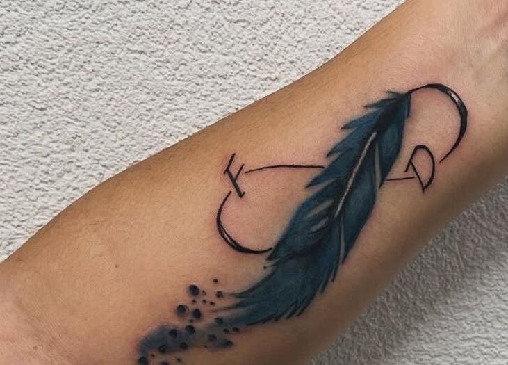 Elegante tatuaggio di piuma blu su avambraccio presso Calaveras Tattoo, Fagnigola, Friuli-venezia Giulia, IT.