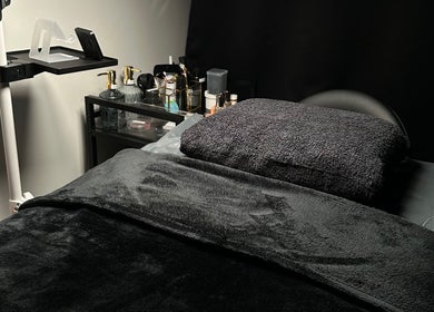 A cozy bed setup at Lash Me, Hounslow, England, GB with plush towels and ambient lighting for relaxation.