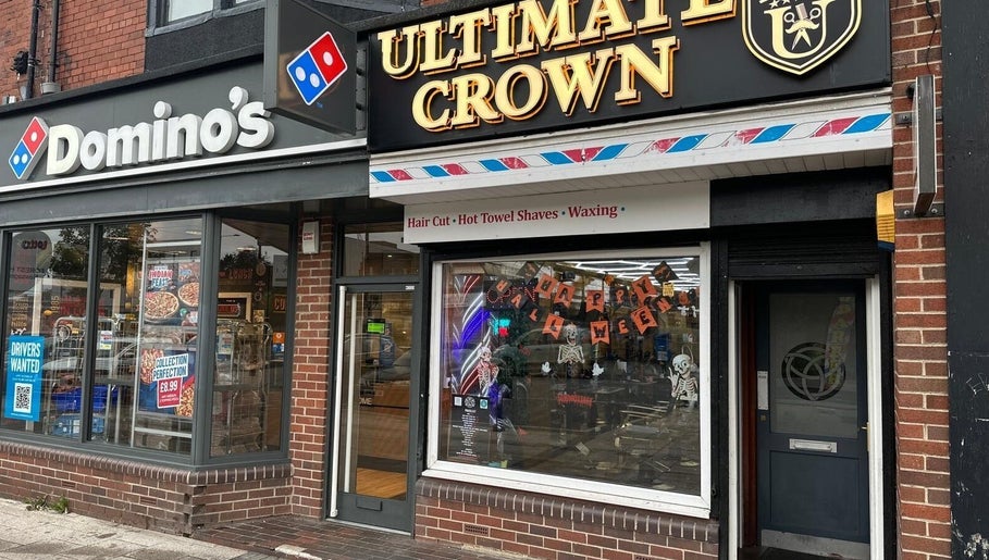 Ultimate Crown Barber storefront, Forest Hall, England, GB, featuring vibrant signage and window display.