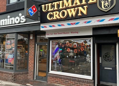 Ultimate Crown Barber storefront, Forest Hall, England, GB, featuring vibrant signage and window display.
