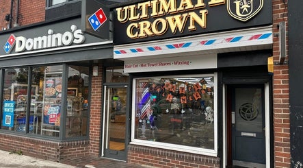 Ultimate Crown Barber storefront, Forest Hall, England, GB, featuring vibrant signage and window display.