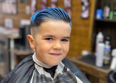 Young boy with bright blue hairstyle at Ultimate Crown Barber, Forest Hall, England, GB.