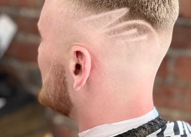 Modern hairstyle with shaved pattern at Ultimate Crown Barber, Forest Hall, England, GB.