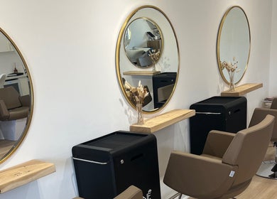 Modern salon setup at Esthétic Hair, Peacehaven, England, GB, featuring elegant round mirrors and stylish chairs.