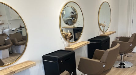 Modern salon setup at Esthétic Hair, Peacehaven, England, GB, featuring elegant round mirrors and stylish chairs.