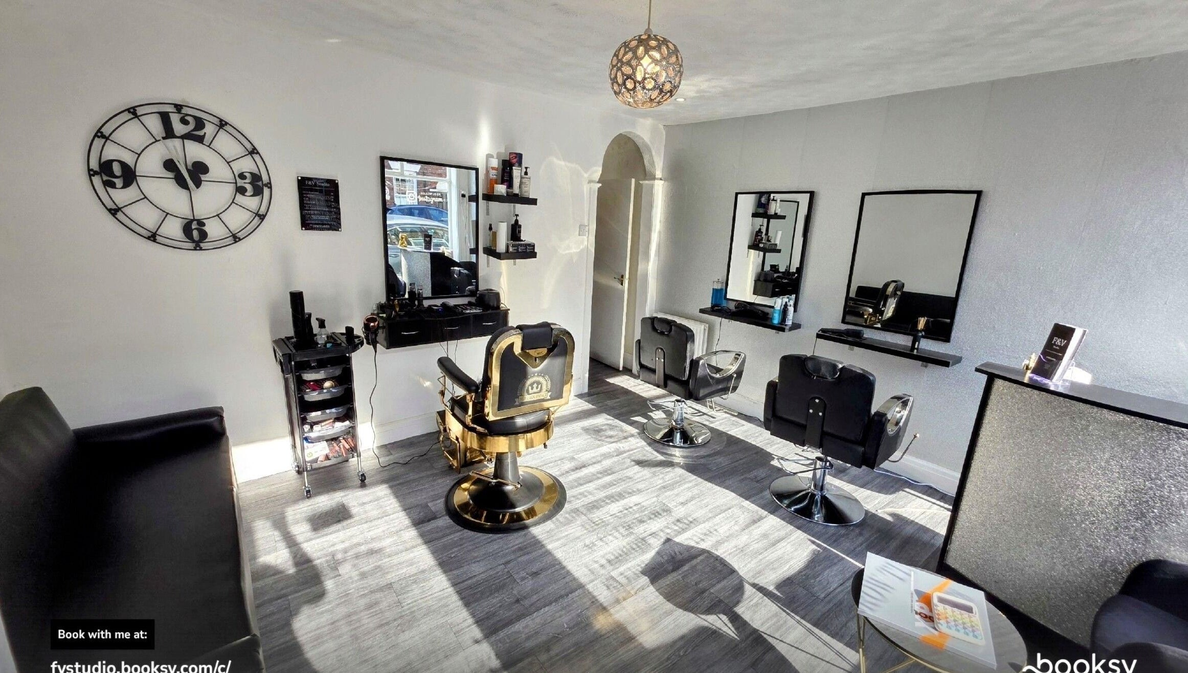 Modern salon interior at Fandvstudio, Macclesfield, England, GB featuring stylish chairs and a large wall clock.