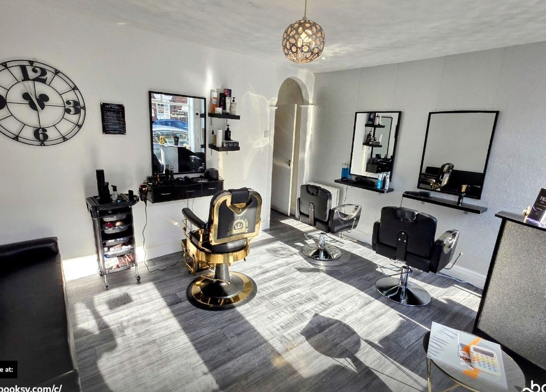 Modern salon interior at Fandvstudio, Macclesfield, England, GB featuring stylish chairs and a large wall clock.