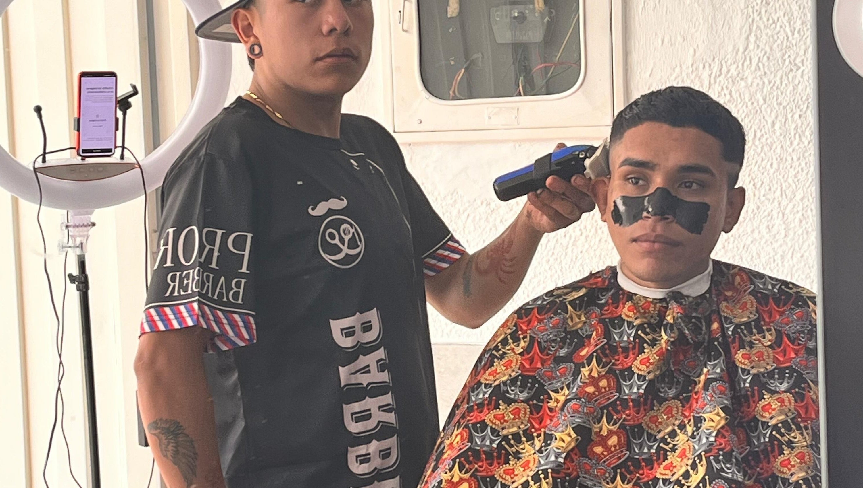 Estilista en The Nick Barber's Bogotá aplicando tratamiento facial durante corte de cabello.