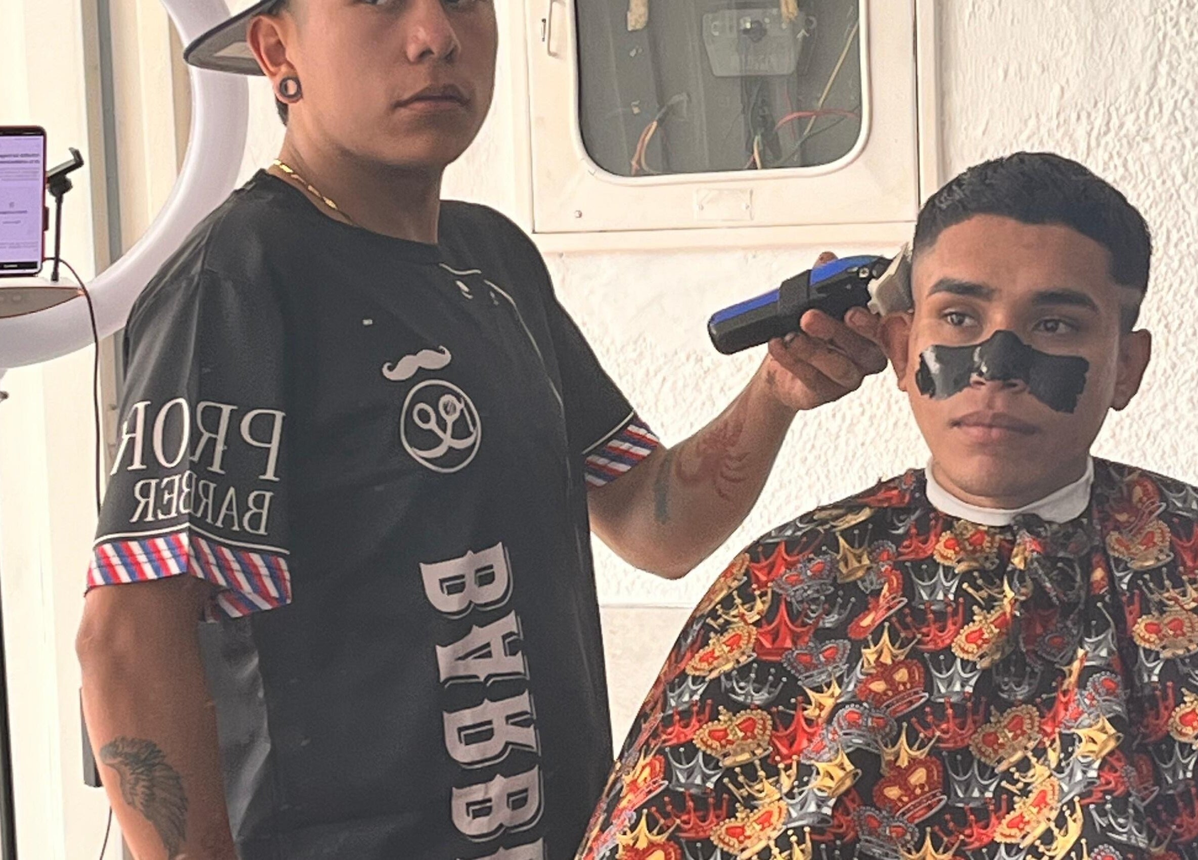 Estilista en The Nick Barber's Bogotá aplicando tratamiento facial durante corte de cabello.