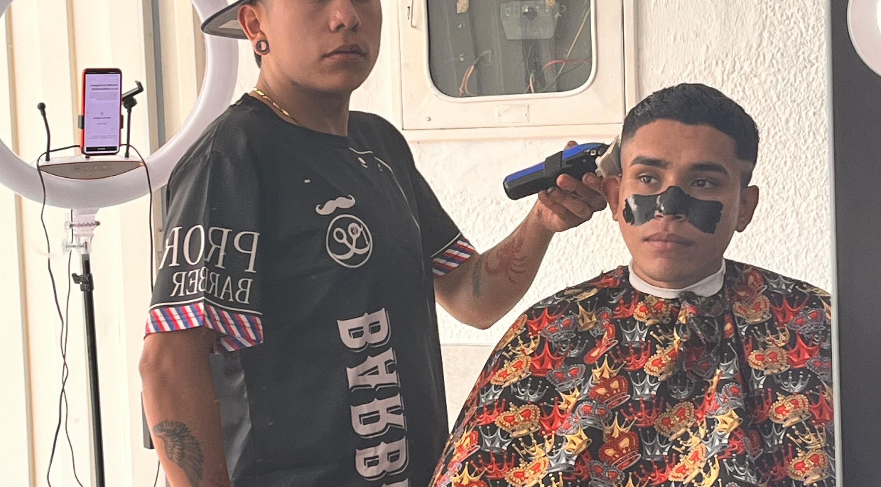 Estilista en The Nick Barber's Bogotá aplicando tratamiento facial durante corte de cabello.