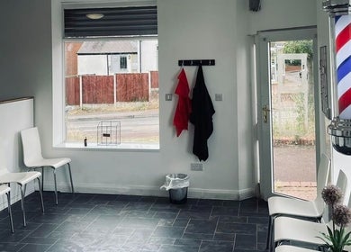 Modern waiting area at Eden At Jacks Barbers in Clipstone, England. Features sleek chairs and iconic barber pole.