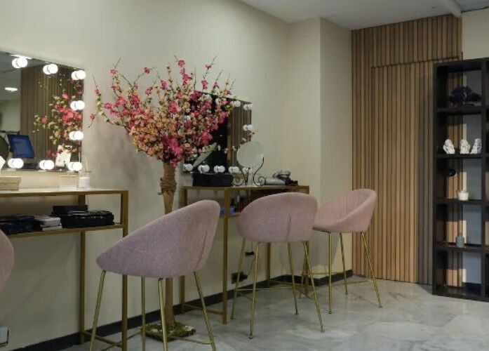 Elegante salón de belleza en Inés Sánchez Beauty Concept, Granada, Andalucía, ES con sillas rosadas y espejo iluminado.