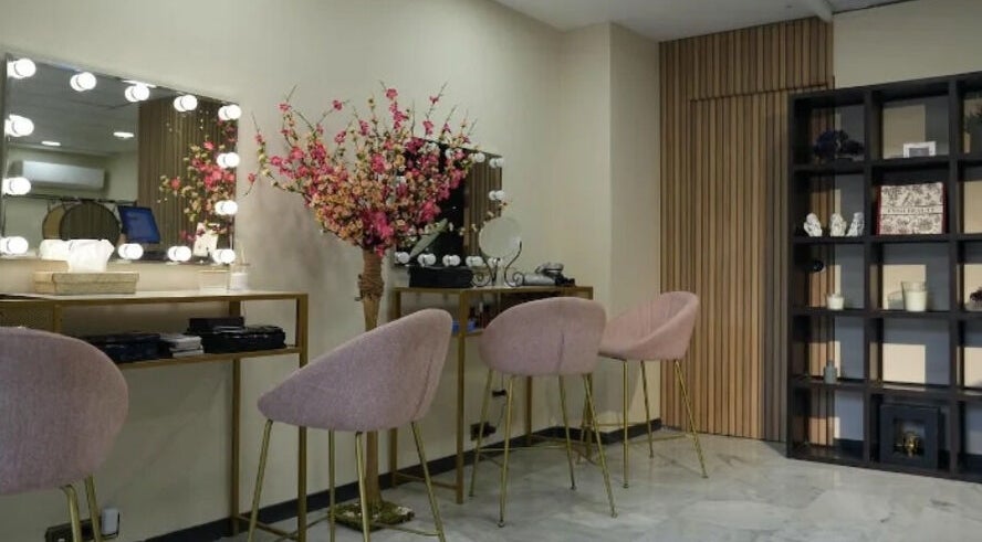 Elegante salón de belleza en Inés Sánchez Beauty Concept, Granada, Andalucía, ES con sillas rosadas y espejo iluminado.