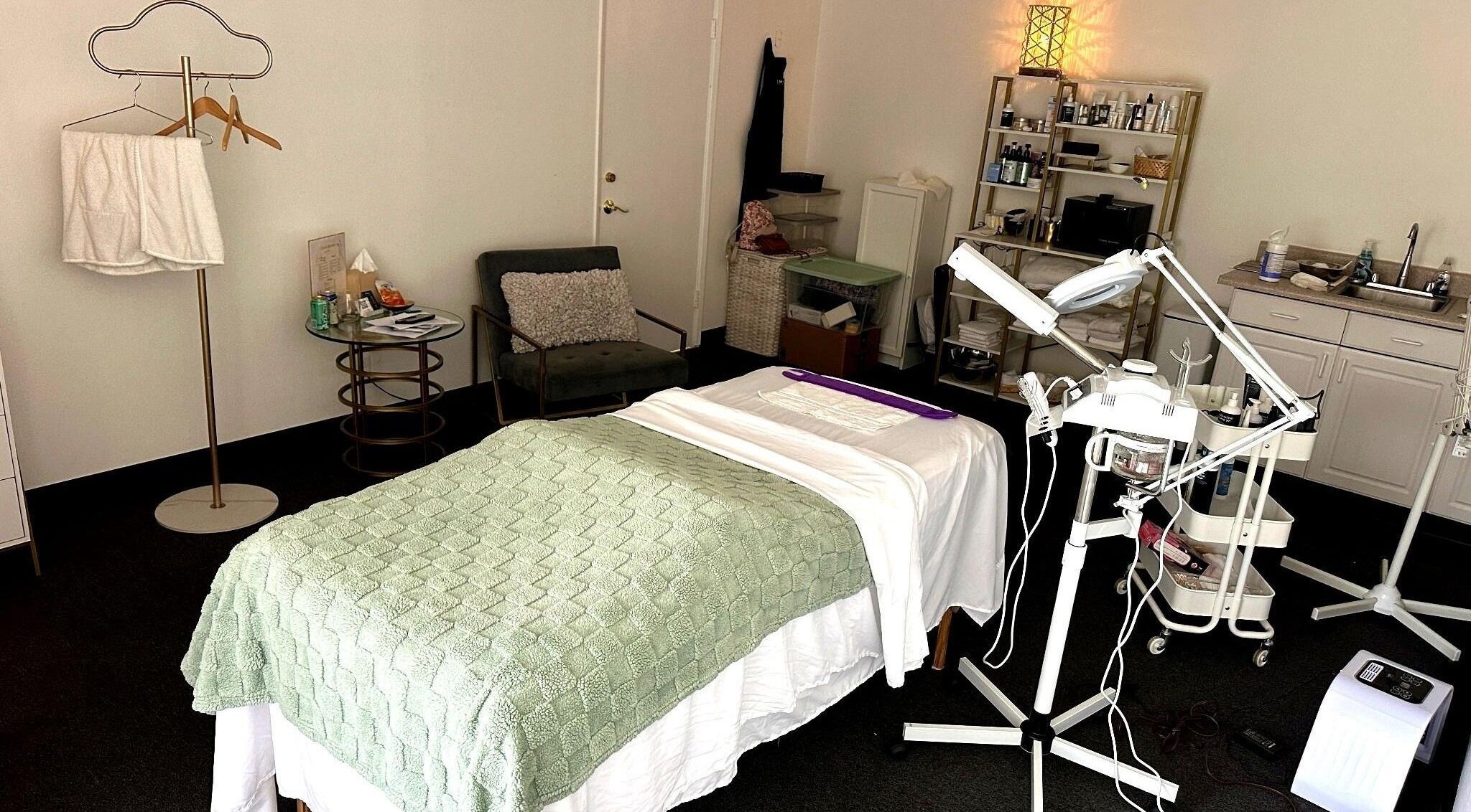 Cozy treatment room at Lash & Glow by Oana, Newport Beach, California, US with bed and equipment.