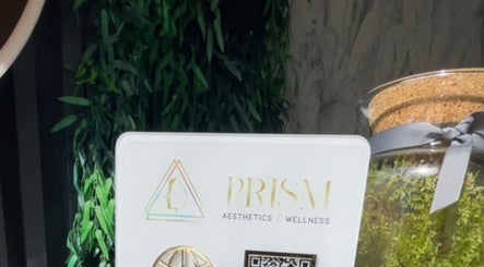 Decorative display at Prism Aesthetics & Wellness, London, England, GB, featuring lush greenery and a logo.