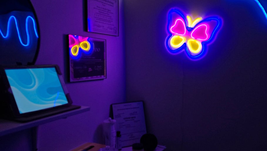 Decoración neón de mariposa en Soft Skin Studio, Coto Laurel, Ponce, PR, creando un ambiente relajante.