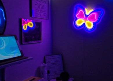 Decoración neón de mariposa en Soft Skin Studio, Coto Laurel, Ponce, PR, creando un ambiente relajante.