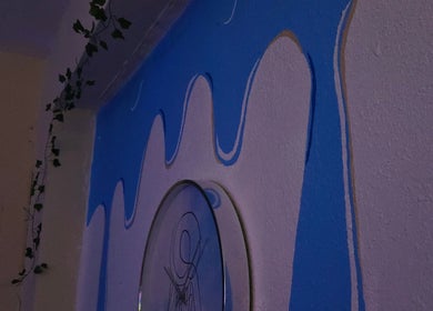 Mural azul vibrante en Soft Skin Studio, Coto Laurel, Ponce, PR con hojas decorativas.