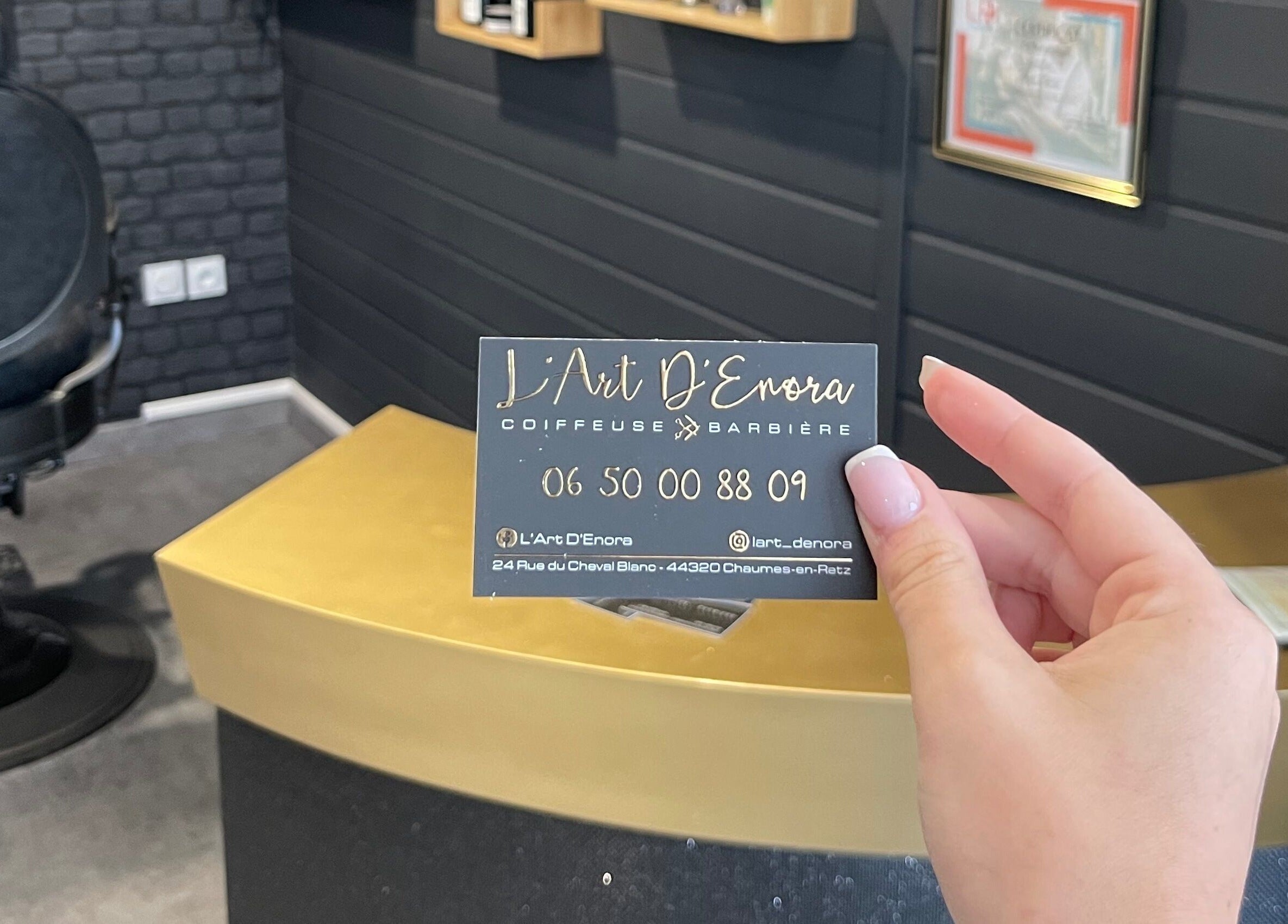 Carte de visite L'Art D'Enora à Chaumes-en-retz, Pays De La Loire, FR, tenue devant un fauteuil de salon.