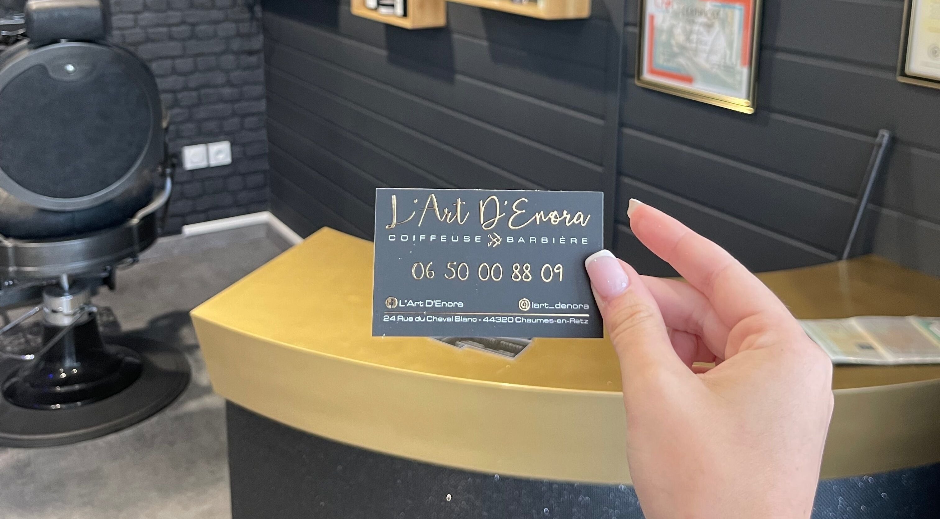 Carte de visite L'Art D'Enora à Chaumes-en-retz, Pays De La Loire, FR, tenue devant un fauteuil de salon.