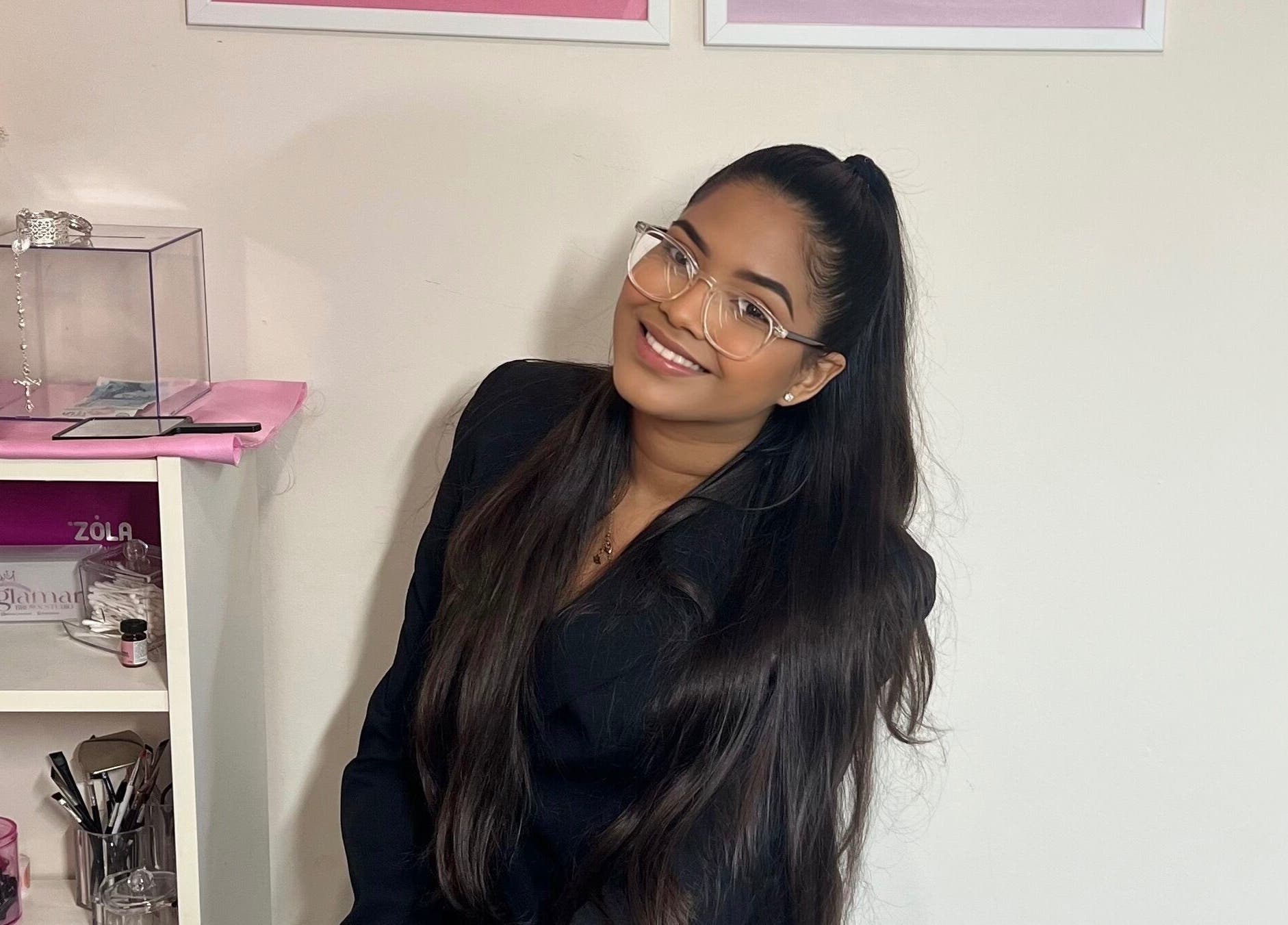 Smiling woman at Glamar brows studio, surrounded by beauty products, London, England, GB.