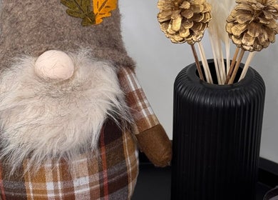 Cozy autumn gnome decor at Matsan_pmu, Utrecht, NL, beside a sleek black vase with pinecones.